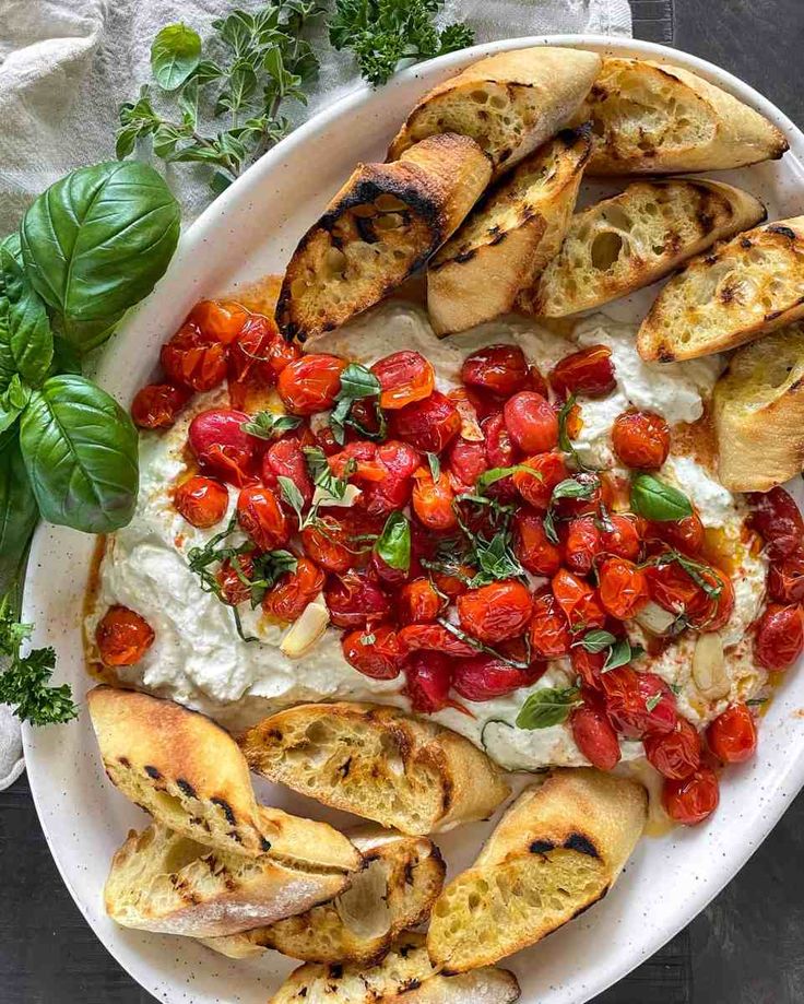 a white plate topped with bread, tomatoes and other toppings on top of it