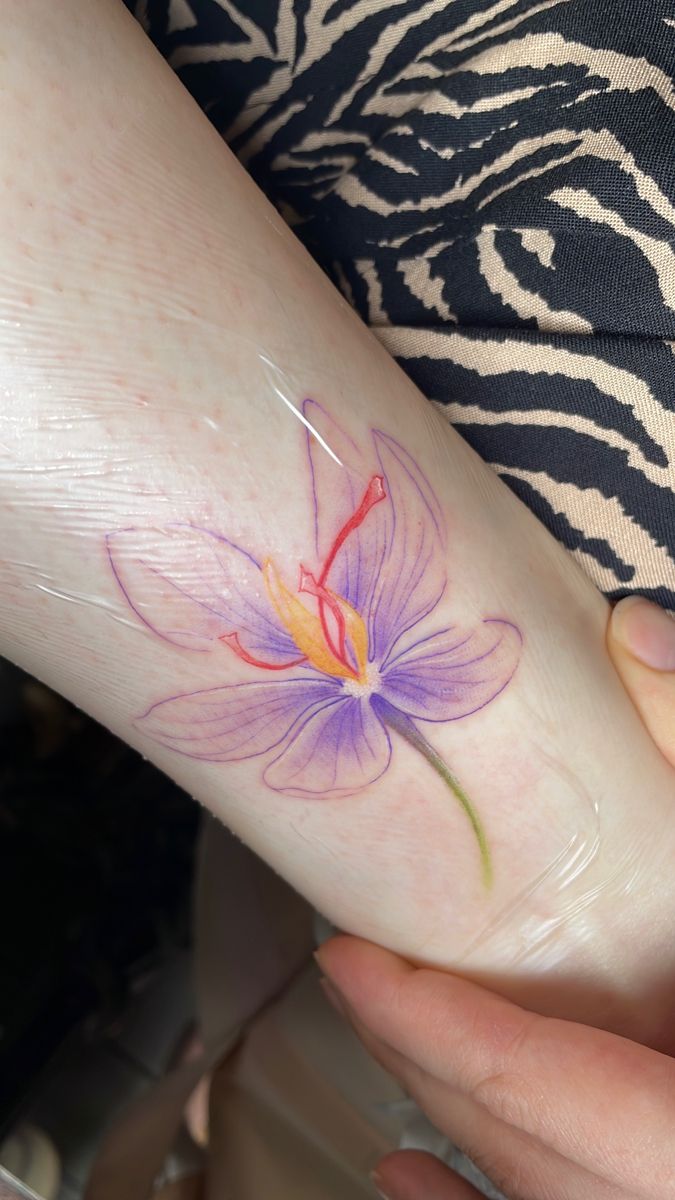 a woman's foot with a flower tattoo on the left side of her leg