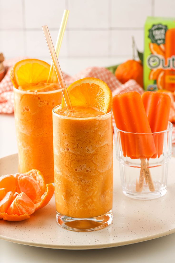 two glasses filled with orange juice next to sliced carrots