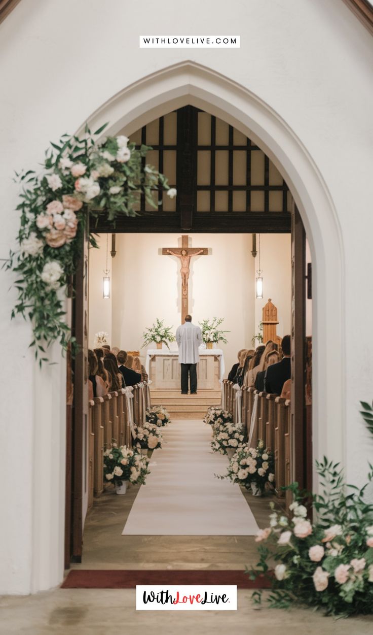 a man standing at the end of a church aisle decorated with flowers and greenery