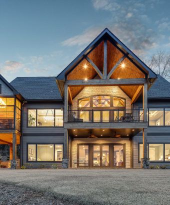 a large house with lots of windows on the front and side of it at dusk