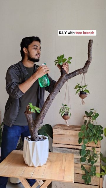 a man standing next to a tree branch holding a green bottle in it's hand