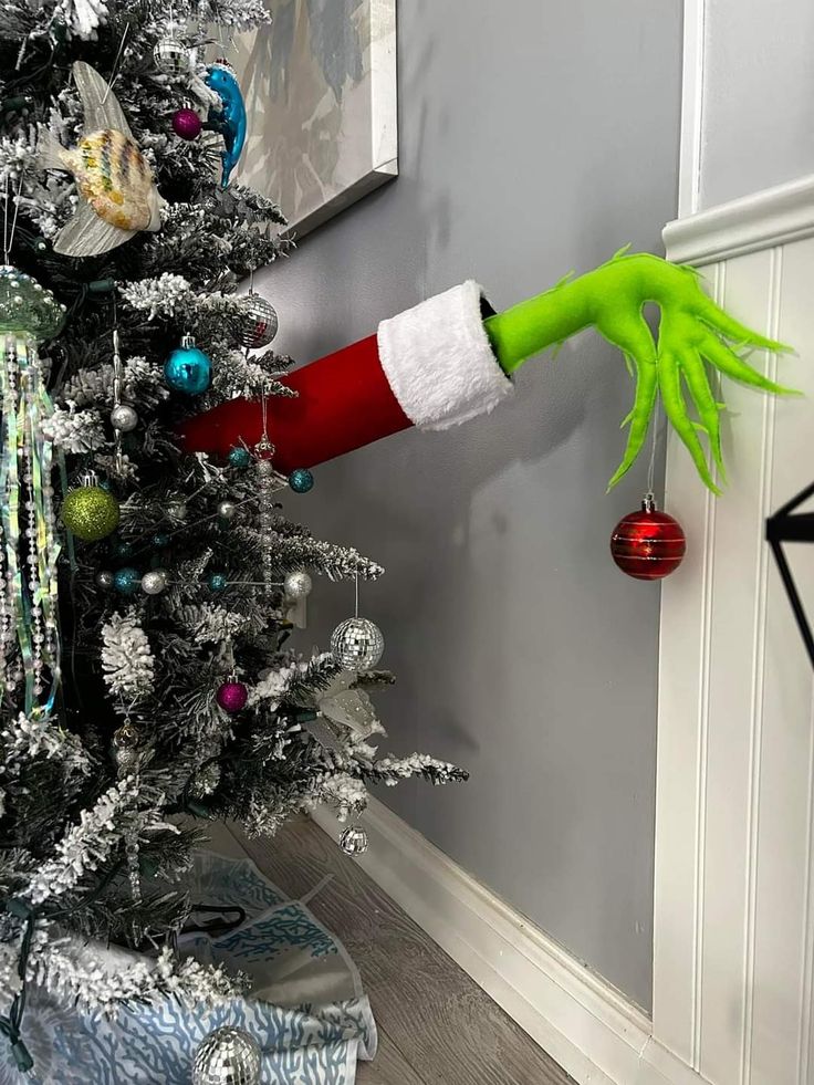 an elf's hand hanging from the side of a christmas tree