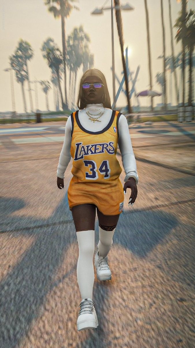 a woman in a lakers jersey is walking down the street with palm trees behind her