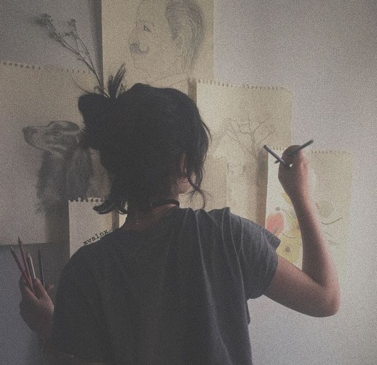 a girl is drawing on the wall with her pencils