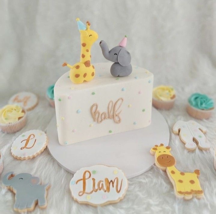 a baby shower cake with giraffes, elephants and cupcakes around it