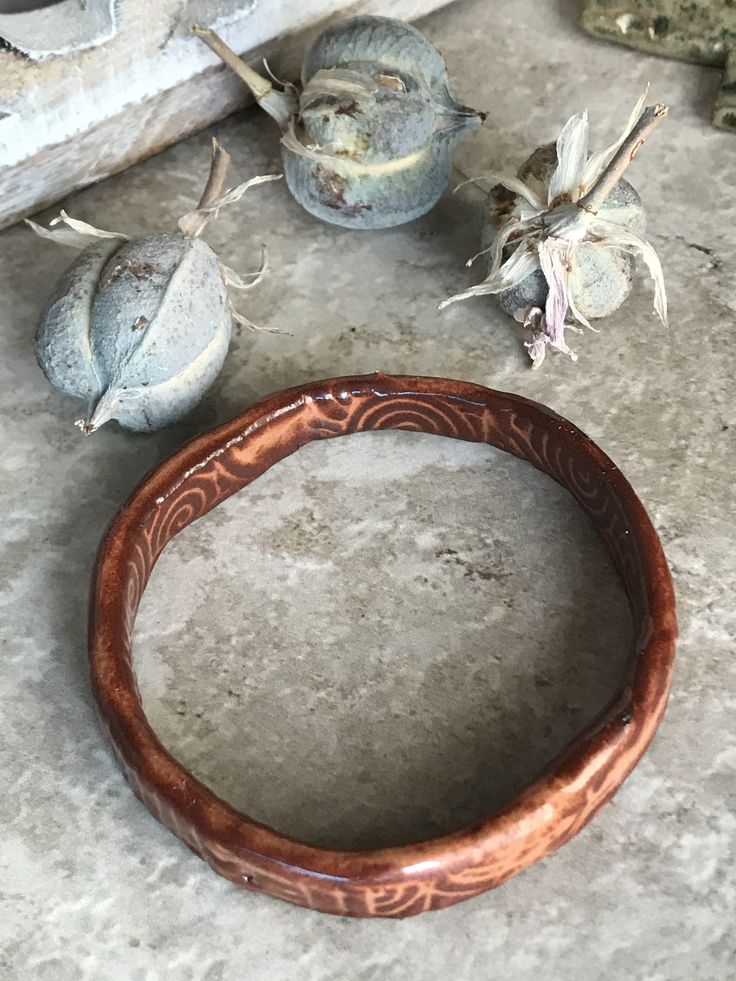 This bracelet will remind you of an ancient relic! However, it has a very glossy sheen. The depth of color and tones are amazing. All sides are glazed. This handmade bracelet was made by me in my studio. Beginning with raw clay, the bracelet was formed, dried slowly, fired in a kiln to 1800 degrees Fahrenheit, dipped in glaze, and then fired again to over 2300 degrees Fahrenheit. This bracelet is 2.5 inches across in the center opening, and because it is closed, be sure to measure one of your cu Artisan Electroformed Bangle Bracelets, Brown Carved Bangle Bracelets, Carved Brown Bangle Jewelry, Artisan Hand Cast Bangle Bracelet, Artisan Hand Cast Bangle Bracelets, Brown Carved Bangle Jewelry, Brown Carved Bracelet Jewelry, Artisan Bangle Bracelet With Patina, Spiritual Carved Bangle Bracelets