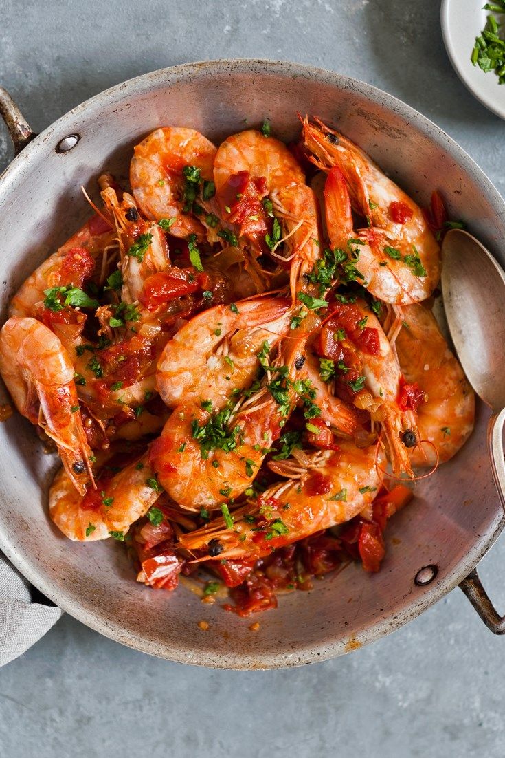 a pan filled with cooked shrimp and garnished with parsley on the side