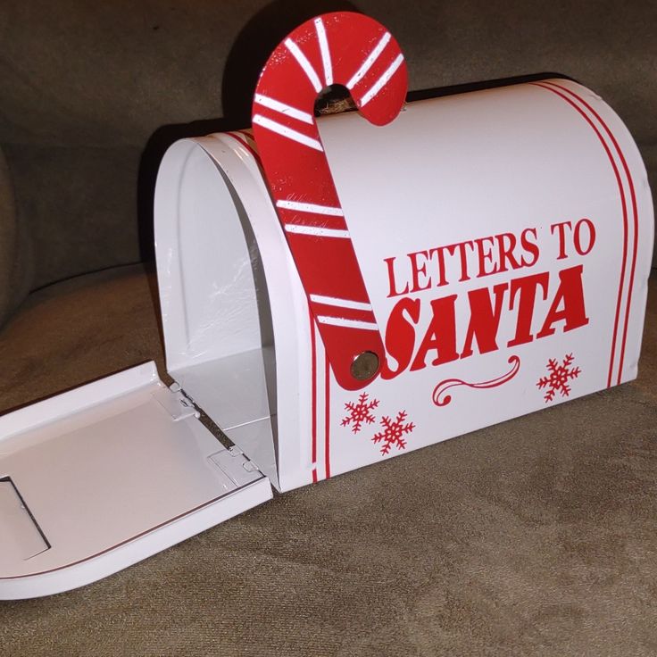 a white mailbox with a red ribbon on it's top and letters to santa written on the front