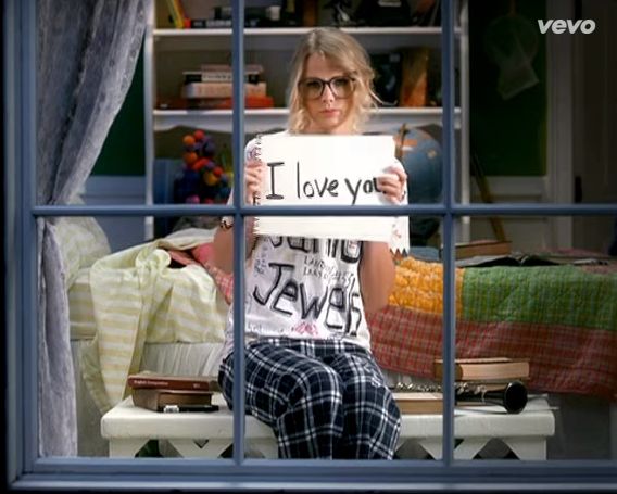 a woman sitting on a window sill holding a sign that says i love you