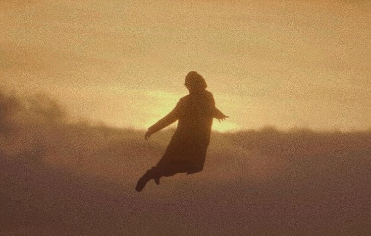 a person is flying through the air with their arms outstretched in front of an orange and yellow sky