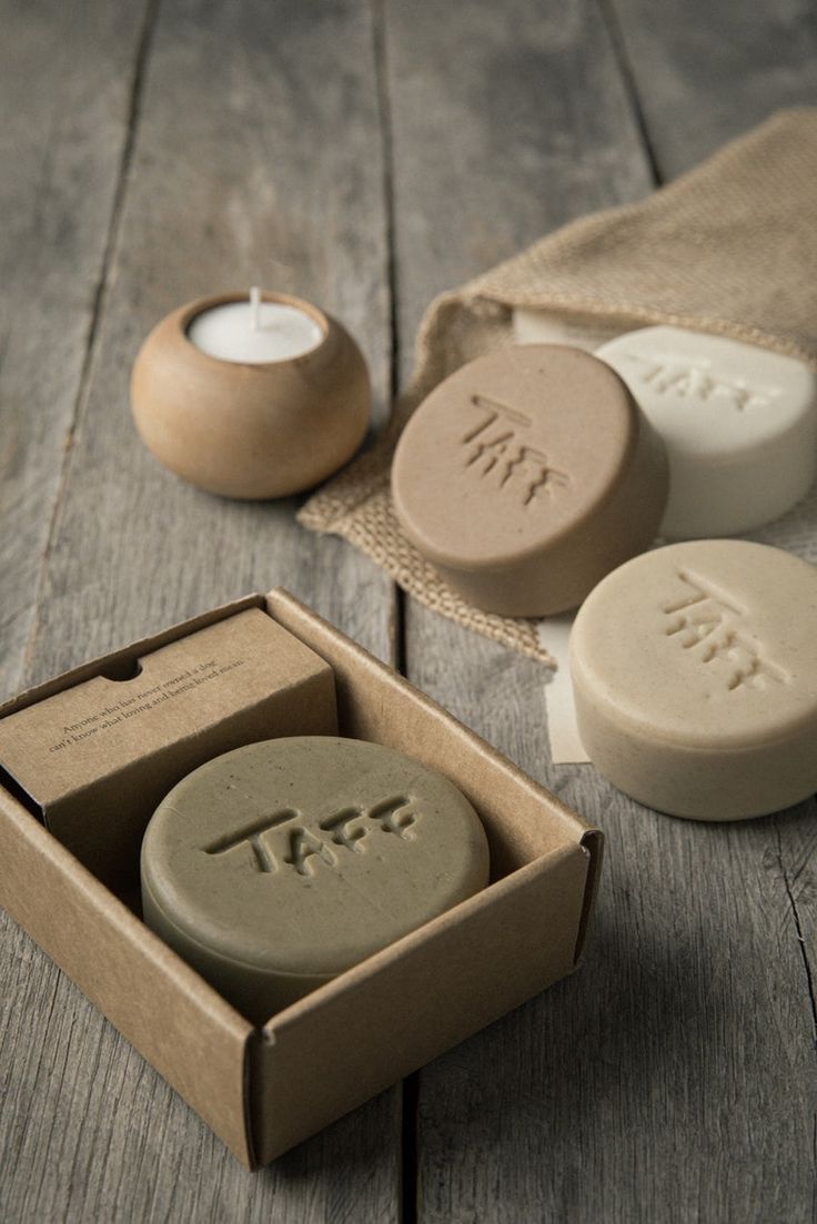 two soaps in a box on a wooden table next to a tea light candle