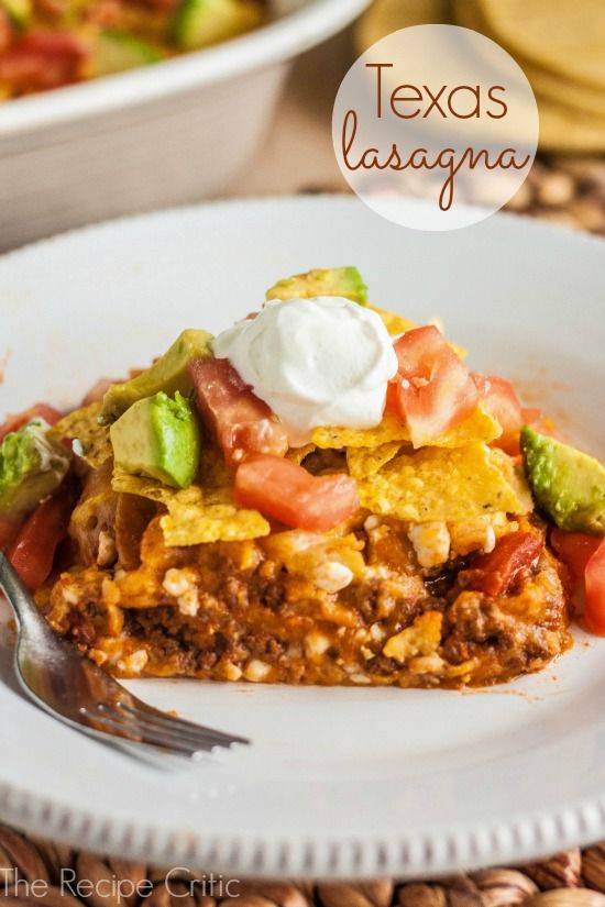 a white plate topped with an enchilada covered in sour cream