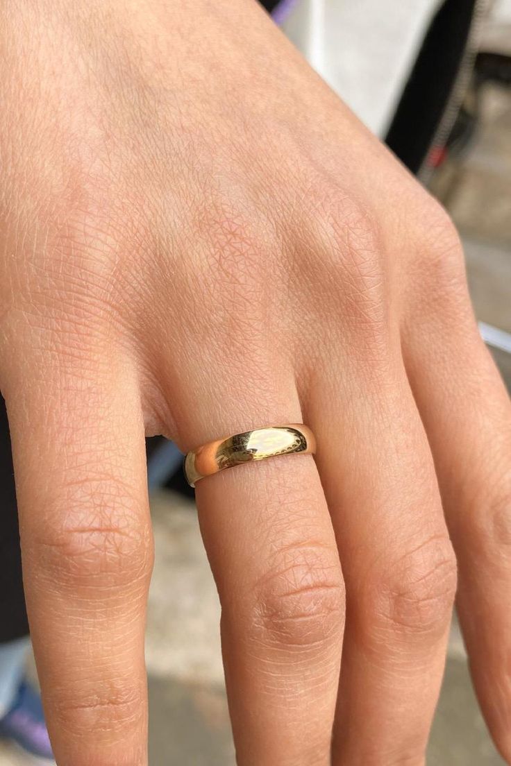 a person's hand with a gold ring on it