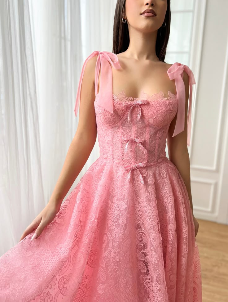 Step into spring celebrations with an air of enchantment in this exquisite midi-length dress, rendered in a delicate rose pink hue that whispers romance. Its bustier top, adorned with a trio of charming bow embellishments, features built-in pads and boning to sculpt and define your silhouette. Crafted from the finest Leavers lace and tulle fabric, it promises a touch of timeless elegance and texture. The dress cinches at the waist before flowing into a graceful midi-length style, complete with i Teuta Matoshi Dresses, Bow Embellishments, Beautiful Ball Gowns, Bow Straps, Beautiful Ball, Dream Wedding Venues, Spring Celebration, Custom Size Dresses, Classy Dress Outfits