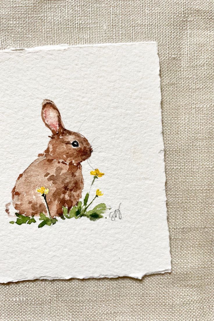 a watercolor painting of a rabbit sitting in the grass with daisies on it's back