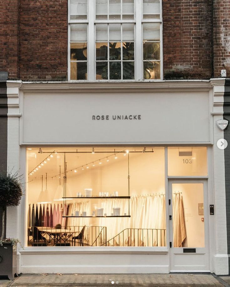 the storefront of rose unnacke is lit up with white lights and windows