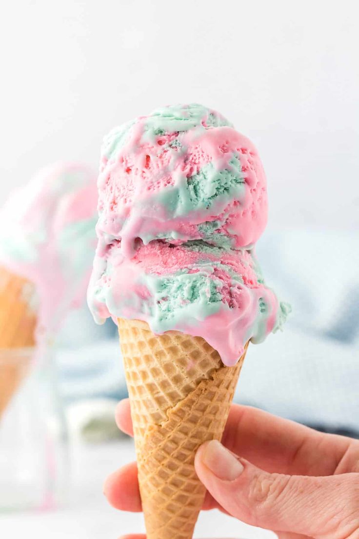 someone is holding an ice cream cone with pink and green sprinkles on it