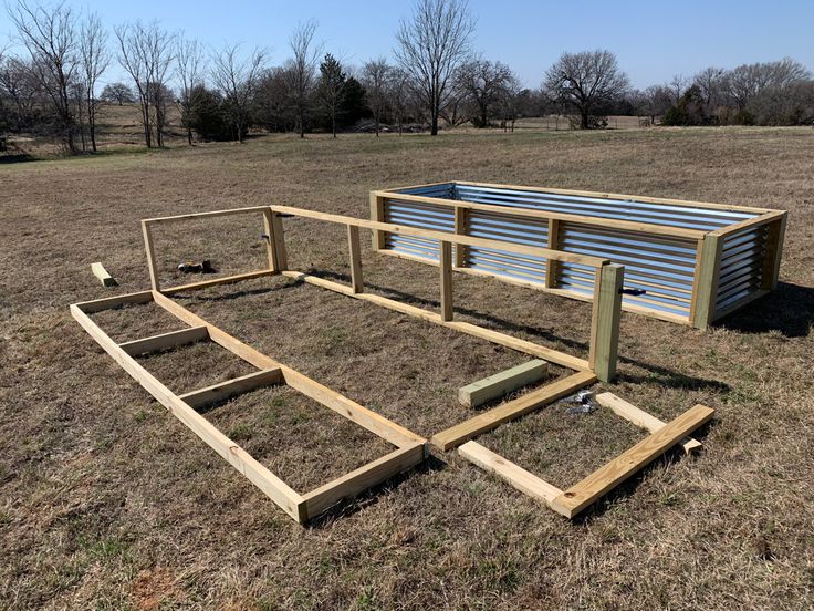 a wooden bed frame sitting on top of a dry grass field