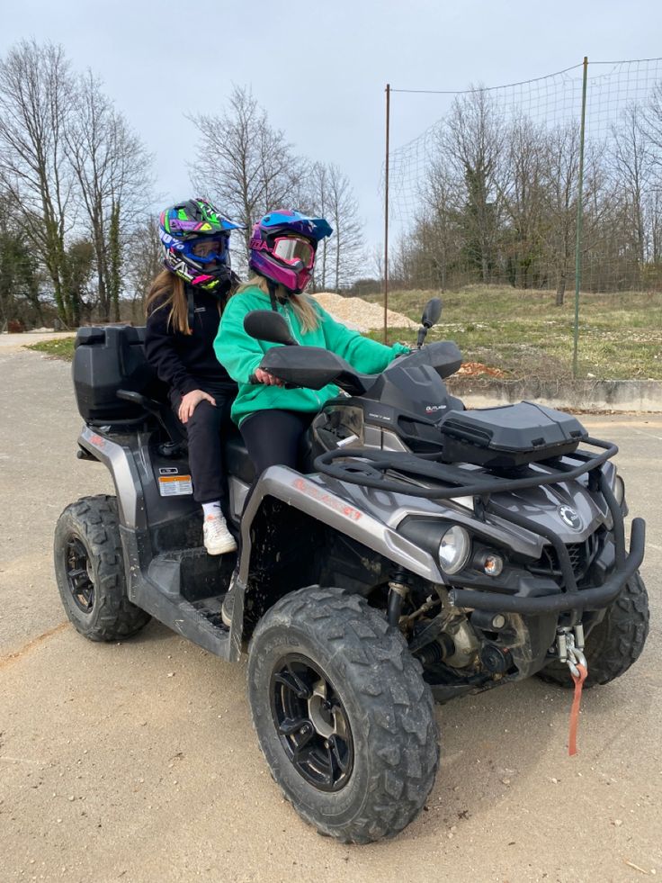 two people riding on the back of an atv