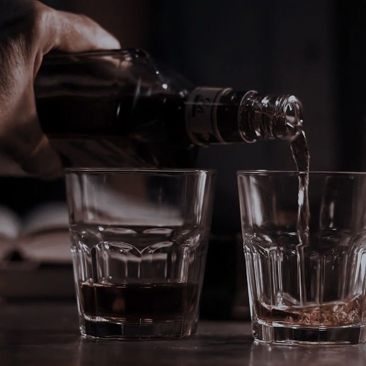 a person pouring some liquid into two glasses