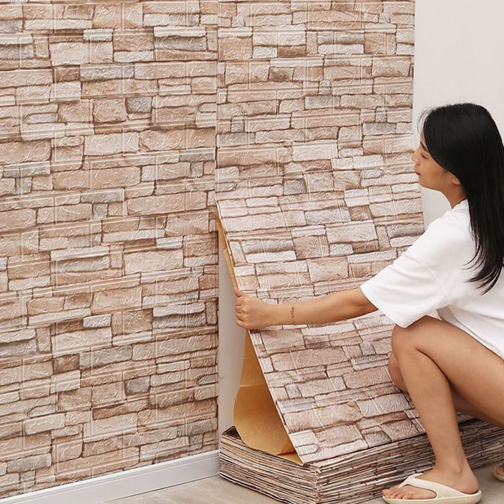 a woman sitting on the floor next to a wall with a cardboard box in front of it