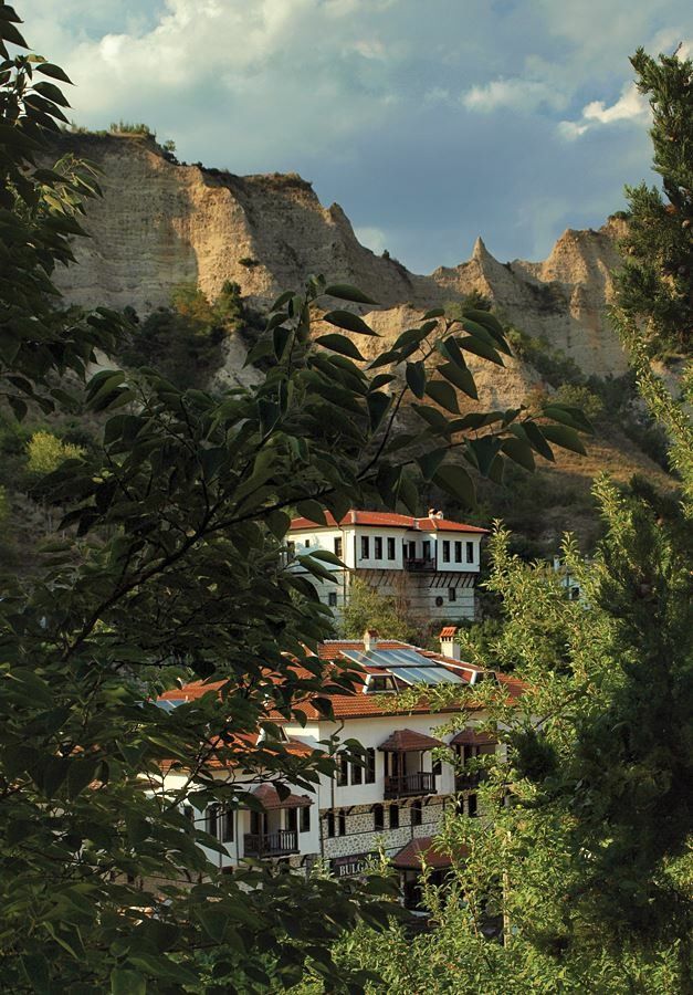 the building is surrounded by trees and mountains