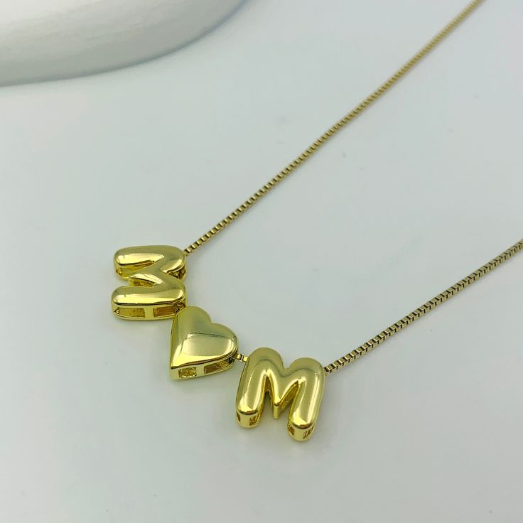 Bring joy and whimsy to your jewelry collection with our Custom Bubble Balloon Letters Necklace. This playful necklace features a delicate gold chain adorned with fun, bubble balloon-shaped letters and special characters like a heart. Perfect for customizing with a name, meaningful word, date, or initials, this necklace adds a touch of lighthearted charm to any outfit. Trendy Personalized Yellow Gold Name Necklace, Trendy Initial Pendant Charm Necklace For Mother's Day, Trendy Initial Pendant Necklace For Mother's Day, Trendy Personalized Charm Necklace For Mother's Day, Trendy Personalized Heart Pendant Charm Necklace, Trendy Initial Necklace For Mother's Day Gift, Mother's Day Birthday Gift Charm Necklace With Adjustable Chain, Mother's Day Gift Initial Necklace With Letter Beads, Mother's Day Birthday Gift Charm Necklace