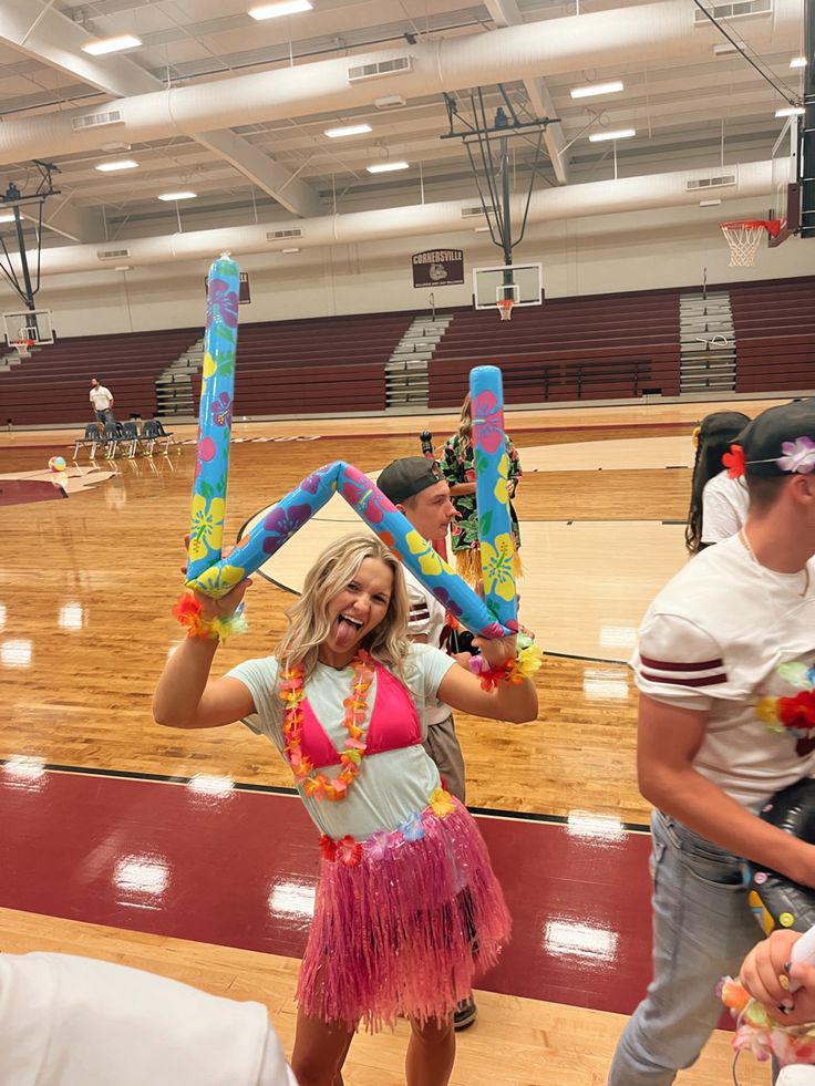 a woman in a hula skirt holding up two large balloons