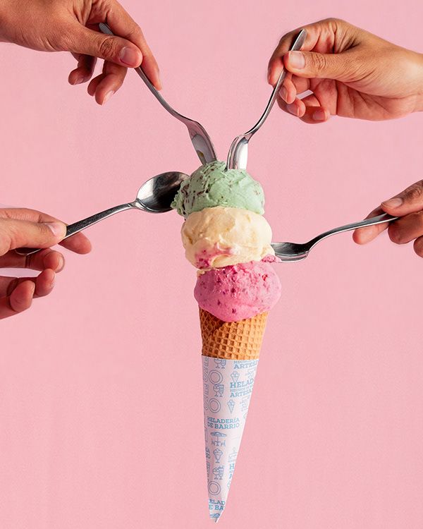 three hands holding spoons and forks over an ice cream cone with scoops in it