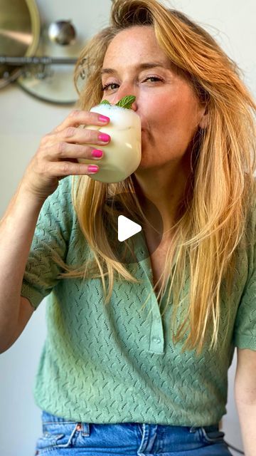 a woman drinking from a cup while sitting down