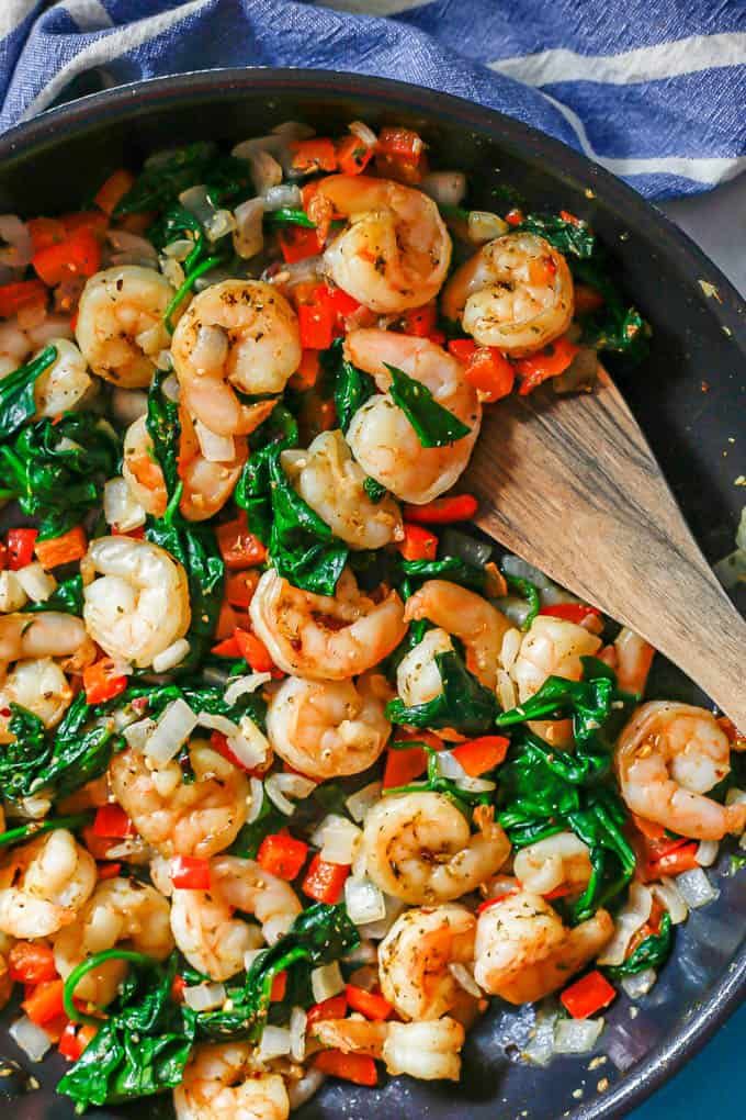 a skillet with shrimp, spinach and carrots in it on a blue towel