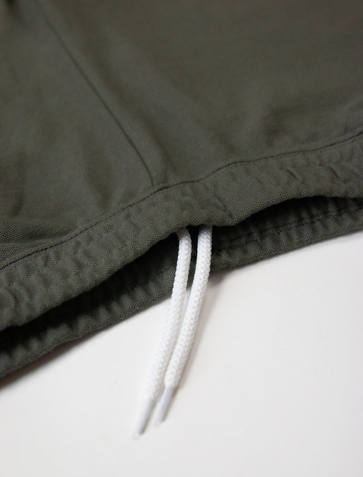 a close up of a green jacket with white string on the bottom and an open zipper