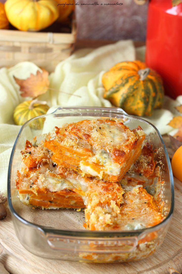 a glass dish filled with lasagna casserole on top of a wooden cutting board