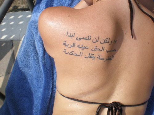 the back of a woman's body with arabic writing on her left shoulder and chest