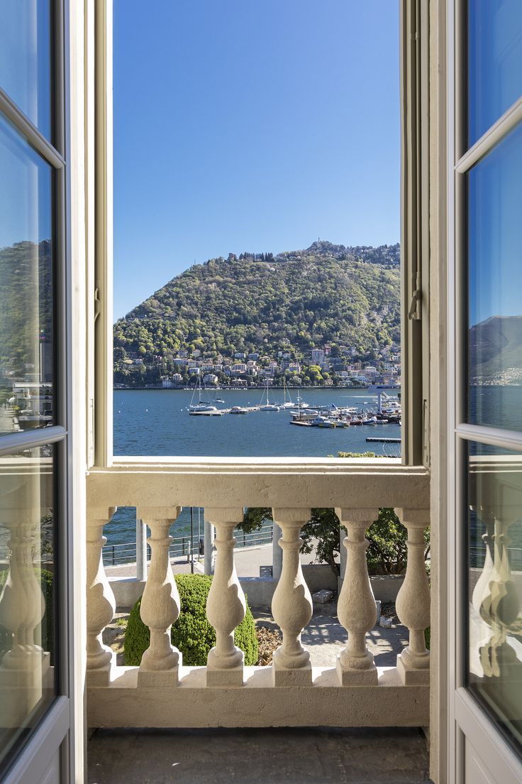 an open window looking out onto a bay with boats on the water and mountains in the distance