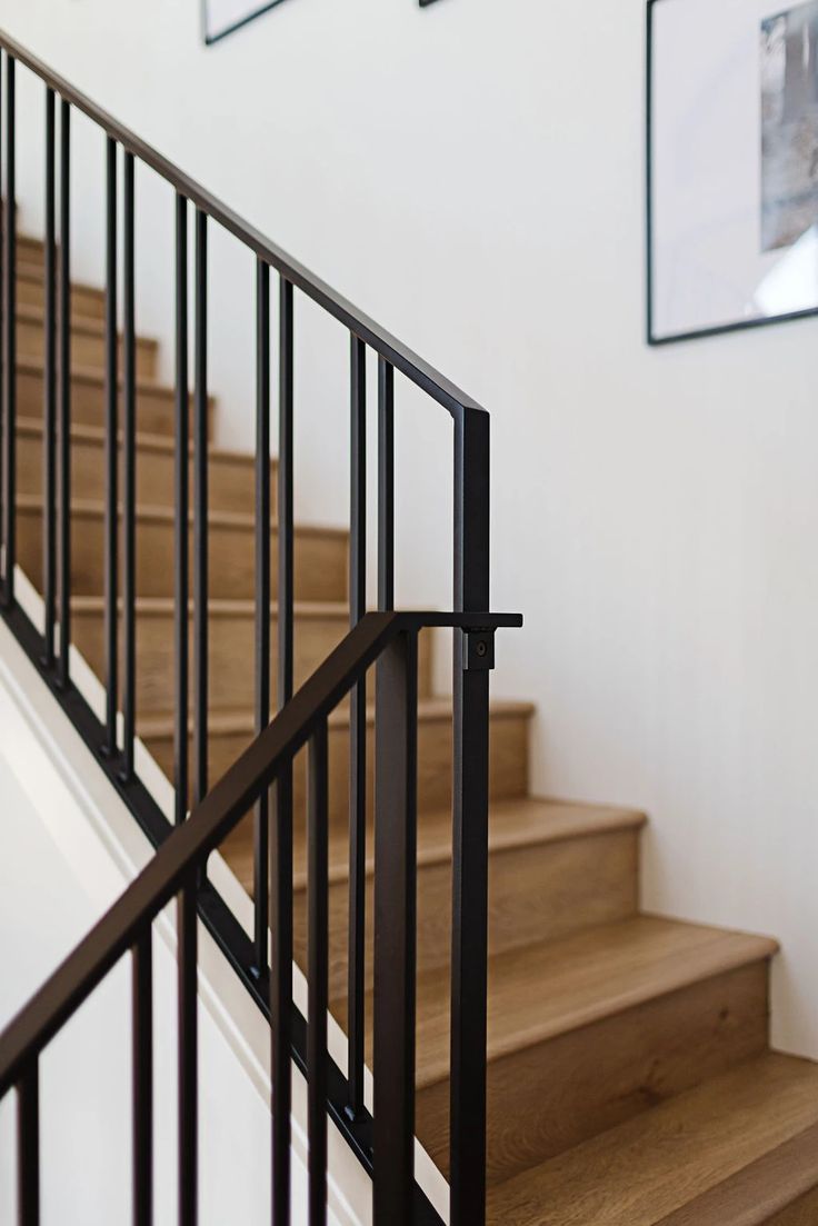 there are pictures on the wall above the stair railing and below the bannister