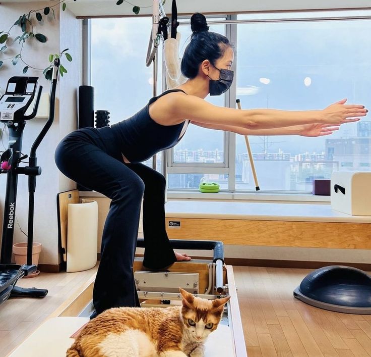 a woman is doing yoga with her cat on the floor in front of an exercise room