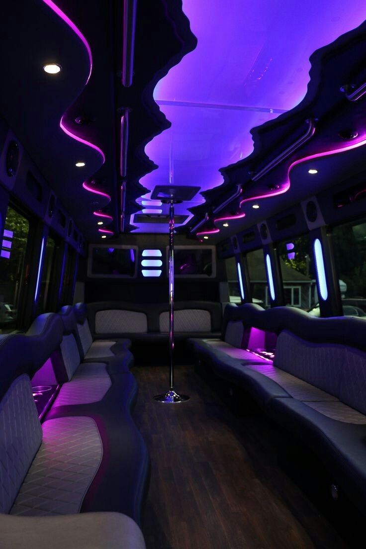 the interior of a bus with purple lights and couches on it's sides