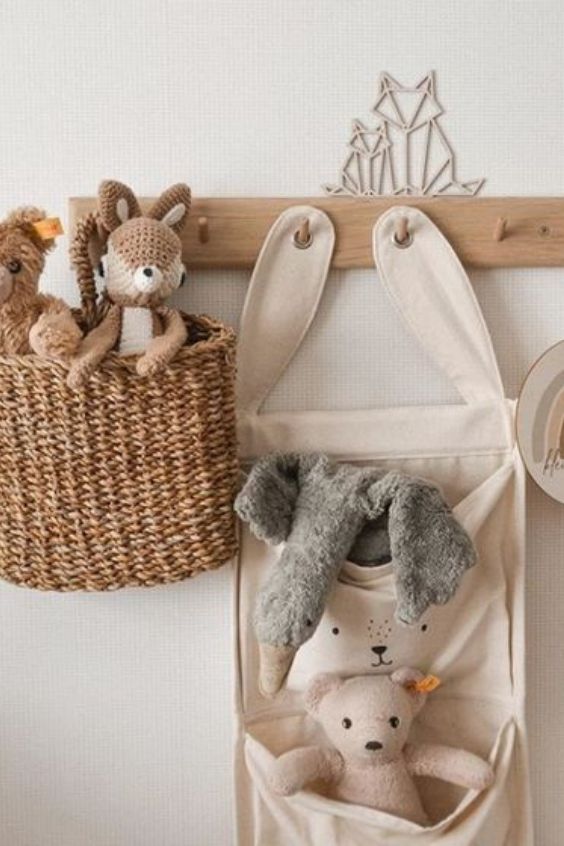 two stuffed animals in a basket hanging on a wall next to a coat rack with hooks