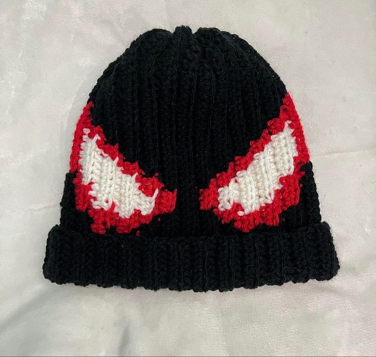 a black and red knitted beanie hat with two white stitchs on it