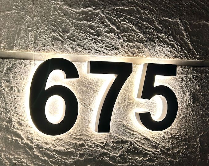 a close up of a number plate on a wall with the numbers 675 written below it