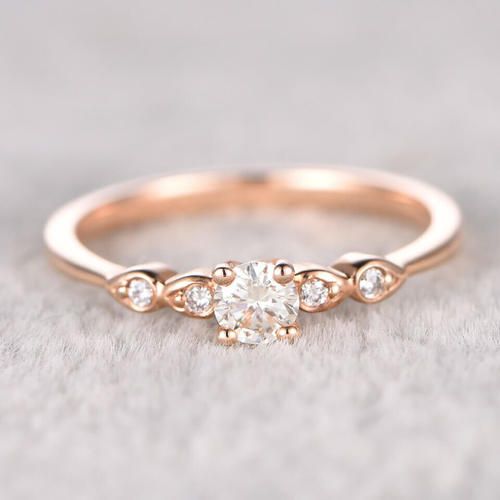 a rose gold engagement ring with three diamonds on the band and an oval shaped diamond in the center