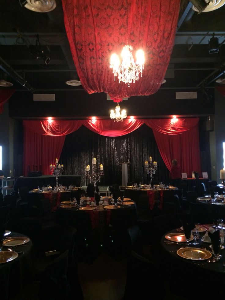 a banquet room set up with red drapes and chandelier hanging from the ceiling