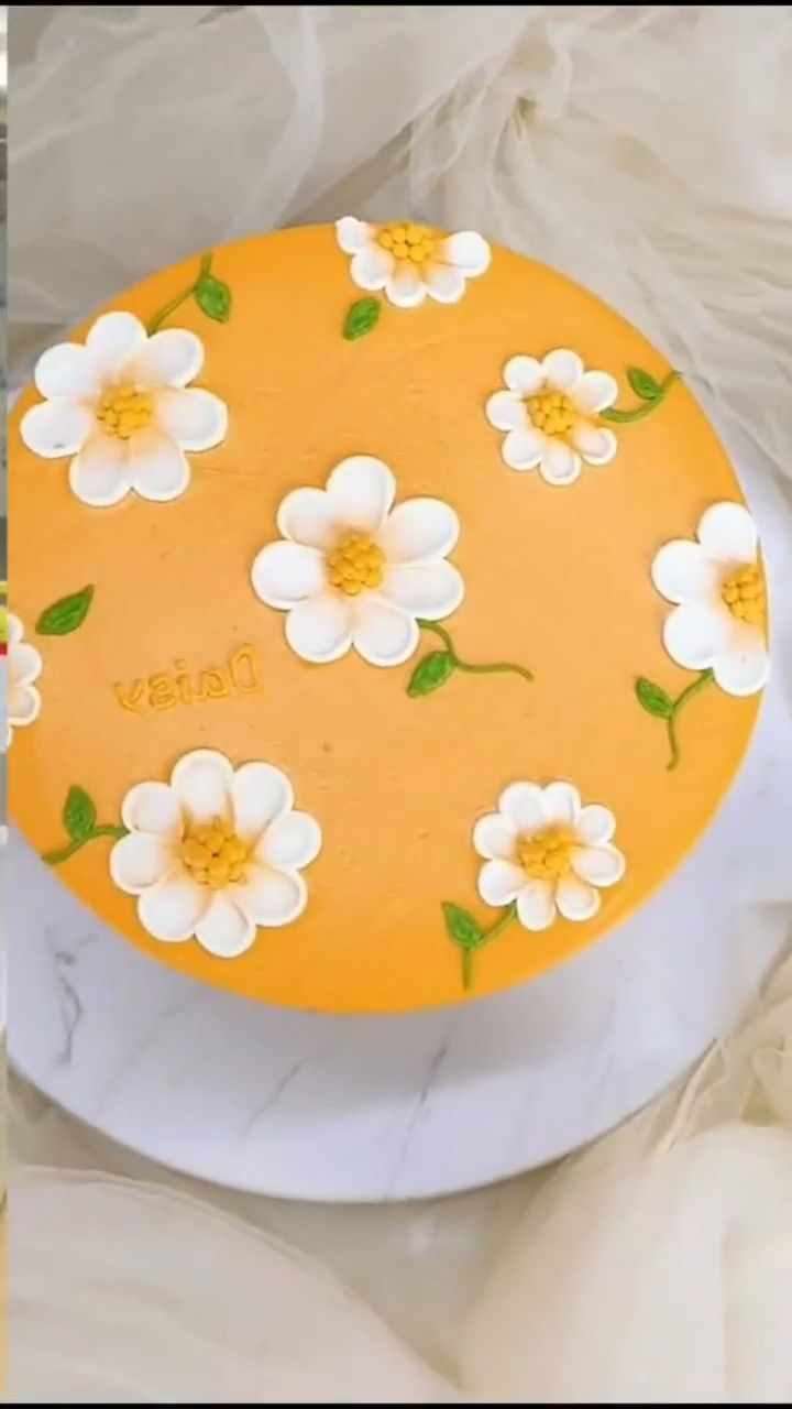 there is a yellow cake with white flowers on it