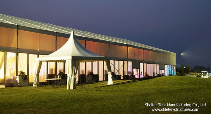 large white tent with curtains and lights on the grass in front of a building at night