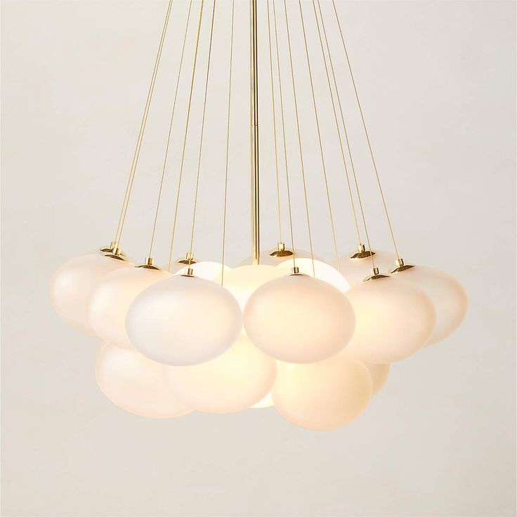 a chandelier with five white balls hanging from it's center and four gold poles