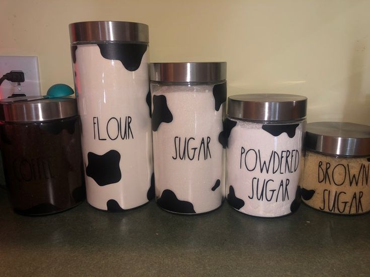 four jars with black and white designs on them sitting on a counter next to each other