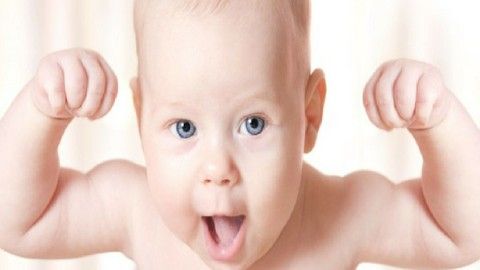 a close up of a baby's face with his hands in the air and eyes wide open