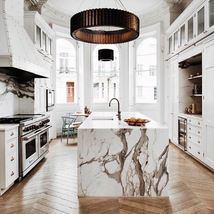 a large kitchen with marble counter tops and white cabinets, along with wooden flooring